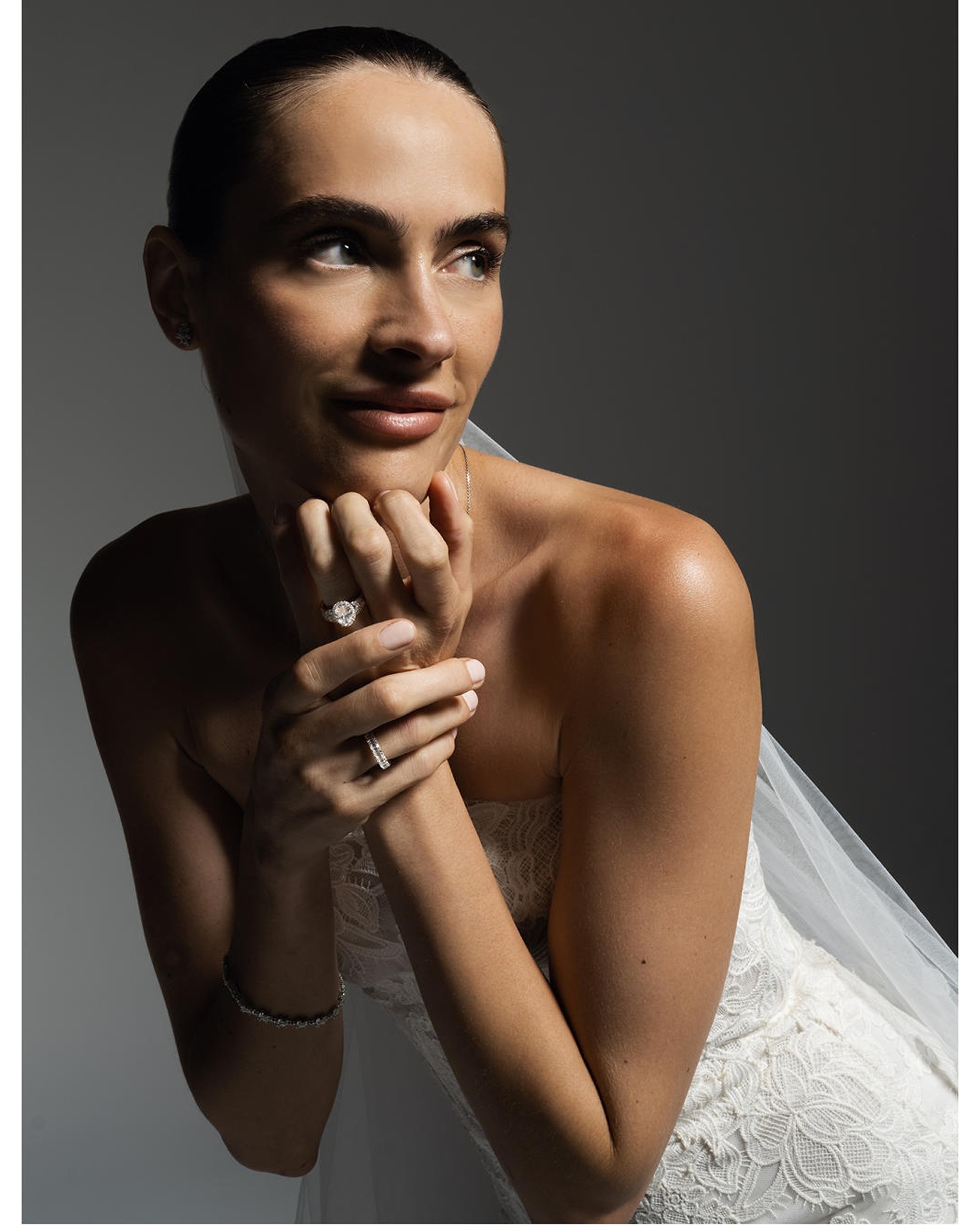 Kay diamond bridal jewelry featuring a striking halo diamond engagement ring, pavé diamond wedding band, diamond stud earrings, and a diamond tennis bracelet showcased in an elegant bridal portrait with a lace wedding gown and veil.