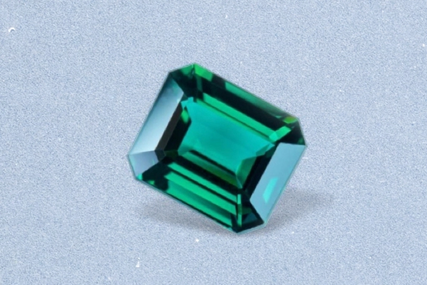 Kay emerald-cut emerald gemstone featuring vivid green color, step-cut facets, and exceptional clarity on a light neutral background