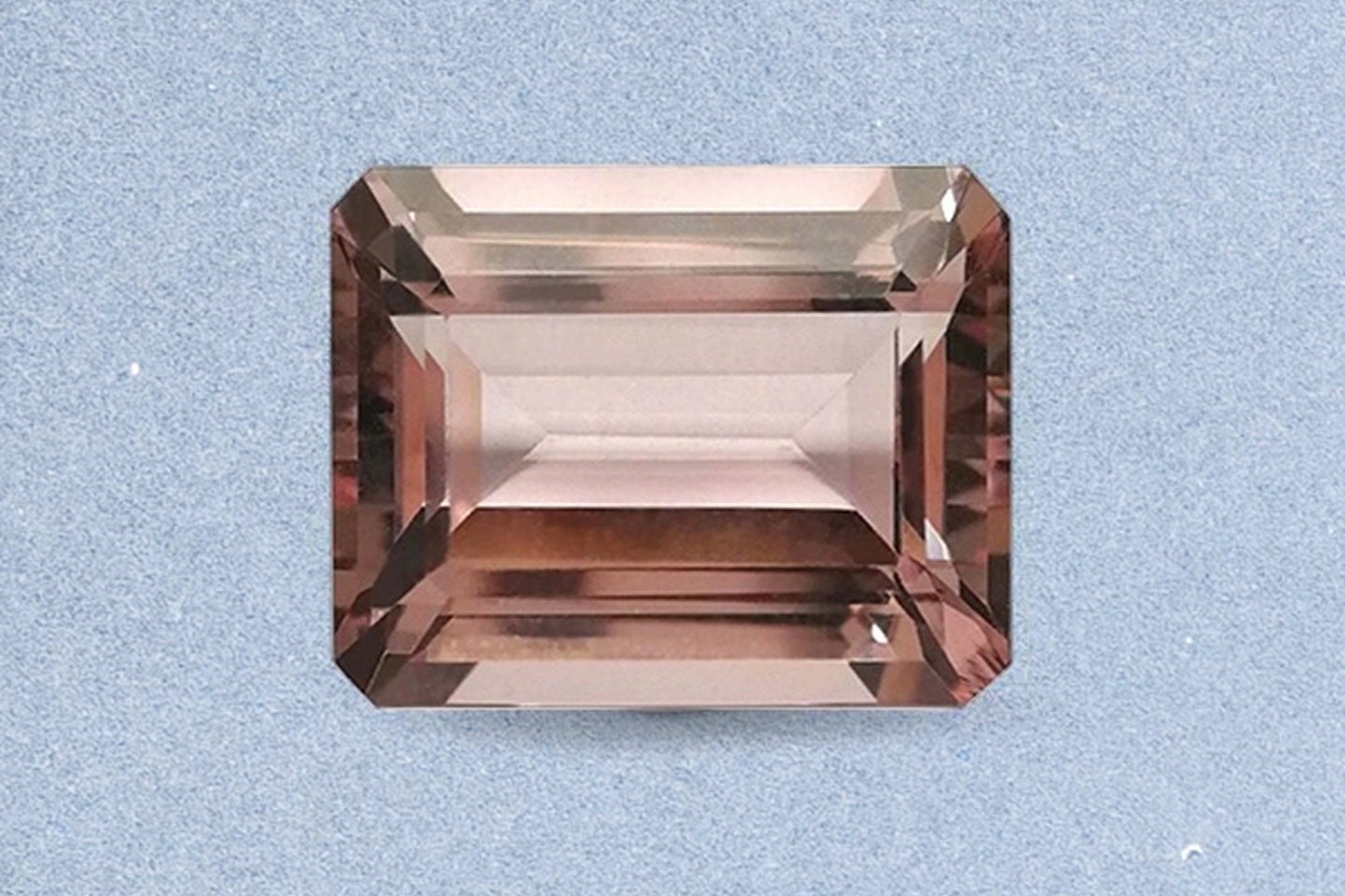 Kay emerald-cut morganite gemstone showcasing soft peach-pink color, elegant step-cut facets, and exceptional clarity against a light neutral background