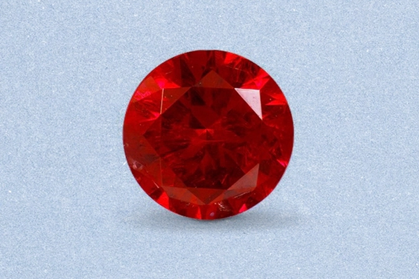 Kay round-cut ruby gemstone featuring vivid red color, brilliant faceting, and exceptional sparkle on a light neutral background
