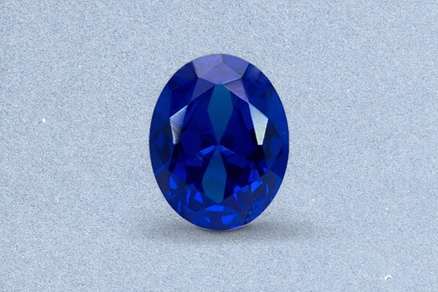 Kay oval-cut sapphire gemstone featuring rich royal blue color, brilliant faceting, and exceptional clarity on a light neutral background