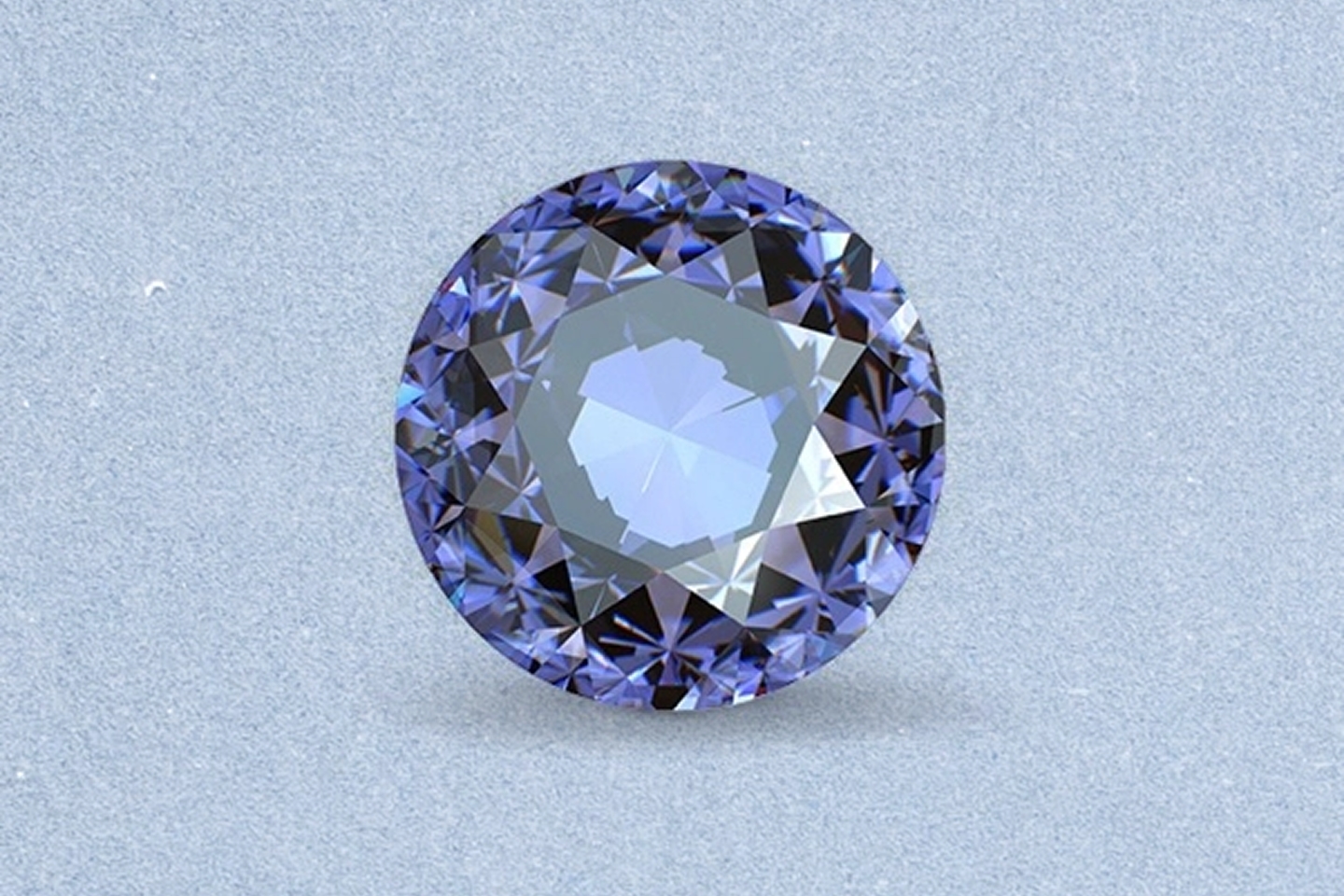 Kay round-cut tanzanite gemstone featuring violet-blue color, brilliant faceting, and exceptional sparkle on a light neutral background