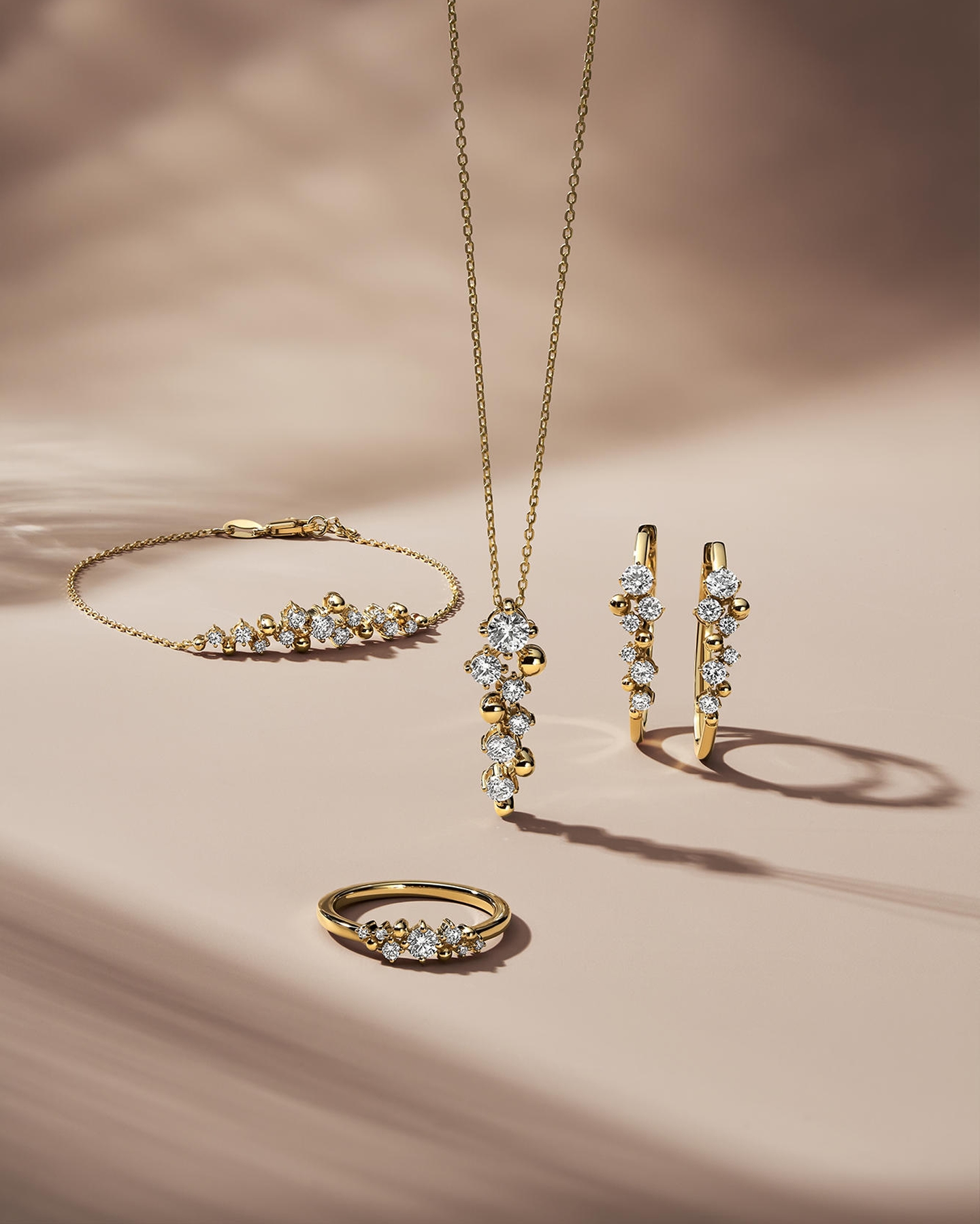 Kay yellow gold diamond jewelry collection featuring a diamond cluster pendant necklace, matching drop earrings, diamond bracelet and diamond ring, styled together to showcase coordinated fine jewelry with modern elegance and radiant sparkle.