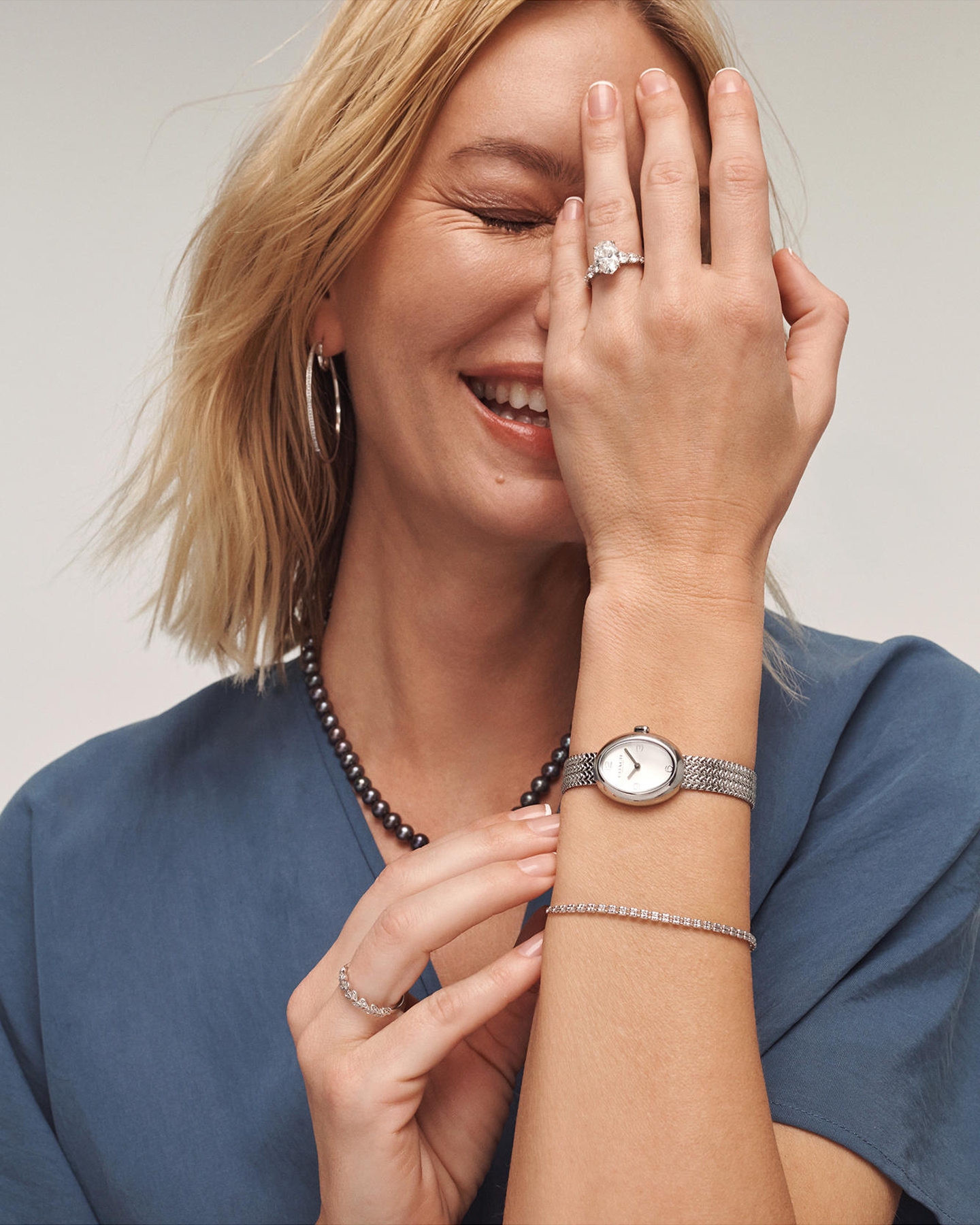 Kay diamond engagement ring paired with a diamond tennis bracelet, silver-tone watch, hoop earrings and pearl necklace, showcasing timeless elegance and everyday luxury.