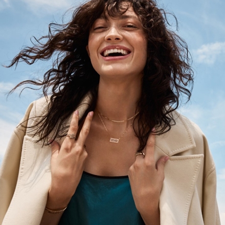 Image of smiling woman wearing two necklaces, two rings, and a bracelet