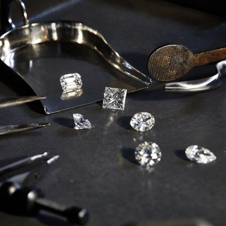 Image of several loose diamonds and jewelry tools