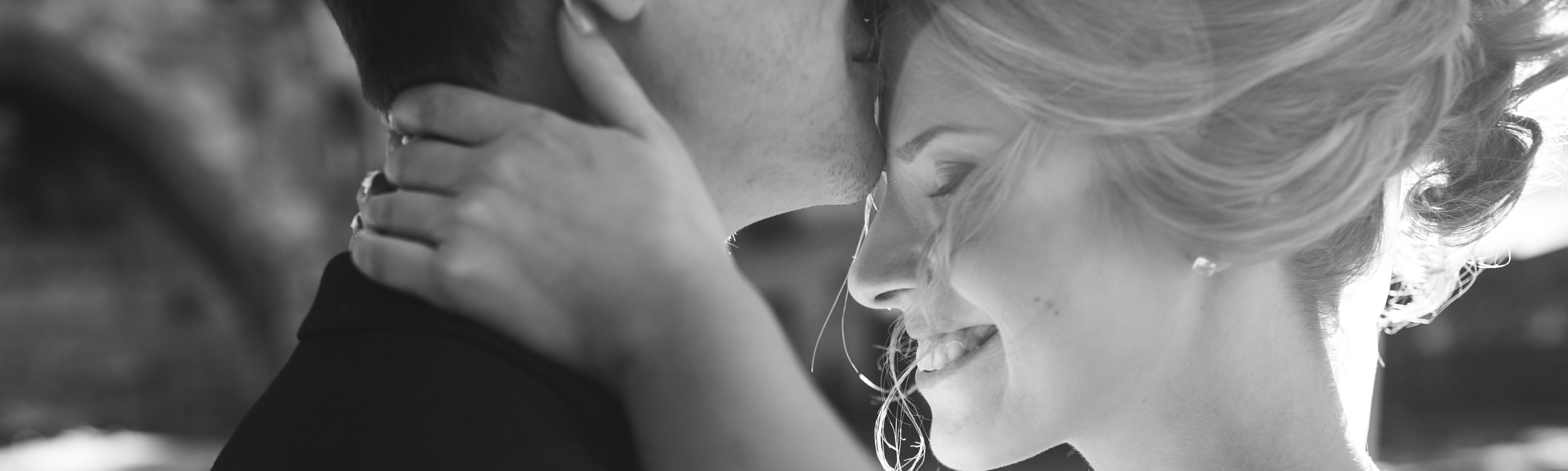 Man kissing his wife's forehead as she smiles and embraces him