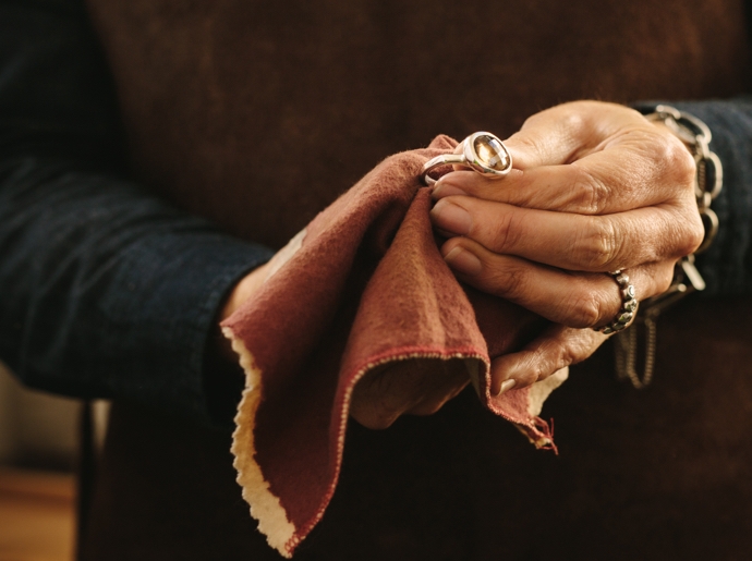 A woman cleaning gemstone jewelry with a cloth.