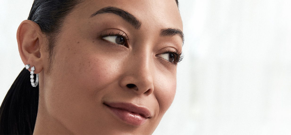 Image of woman smiling, wearing diamond hoop and stud earrings