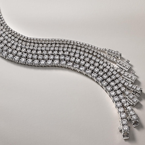 A row of seven silver, diamond-studded tennis bracelets and necklaces from KAY.