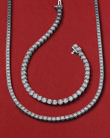 A diamond tennis necklace wrapped around a diamond tennis bracelets, from KAY.