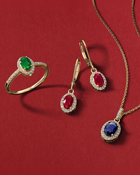 An emerald ring, a set of ruby earrings, and a sapphire pendant chain necklace, all in gold, from KAY.