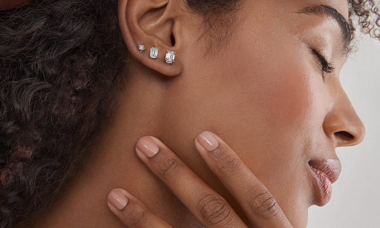 A woman showing off three differing sizes of diamond studs from KAY.