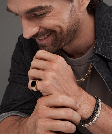 A man wearing a black diamond ring, with a stainless steel and diamond tennis bracelet from KAY.