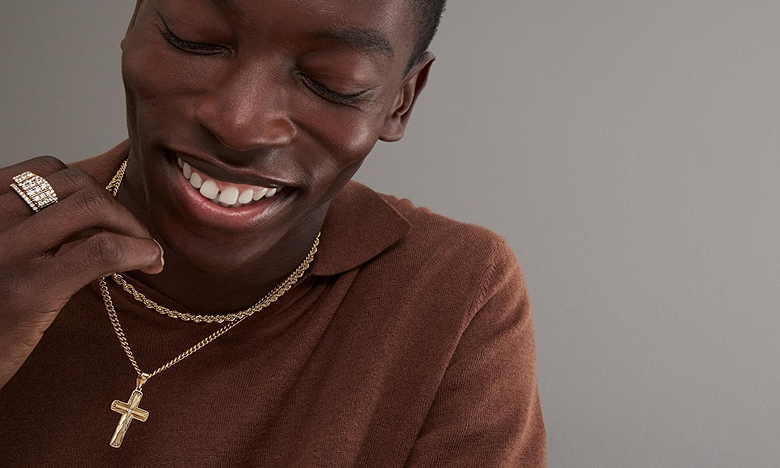 A man wearing a diamond ring, with two gold chains. One of the chains has a diamond studded cross, from KAY.