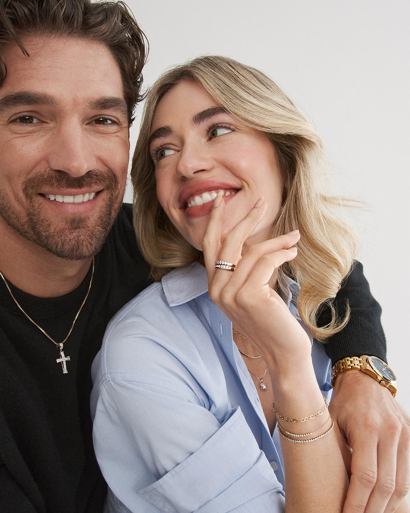 A man with his arm around a woman's shoulder. Both are wearing various classic jewelry pieces from KAY.