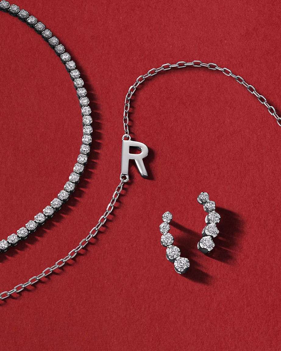 A diamond tennis bracelet, silver chain link necklace, and set of diamond stud earrings by Rocksbox, from KAY.