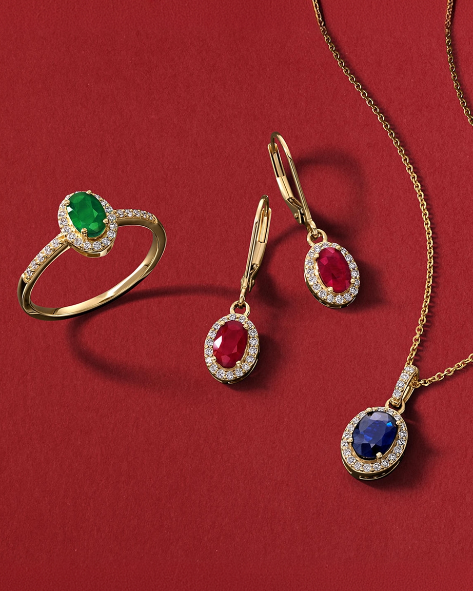 An emerald ring, a set of ruby earrings, and a sapphire pendant chain necklace, all in gold, from KAY.