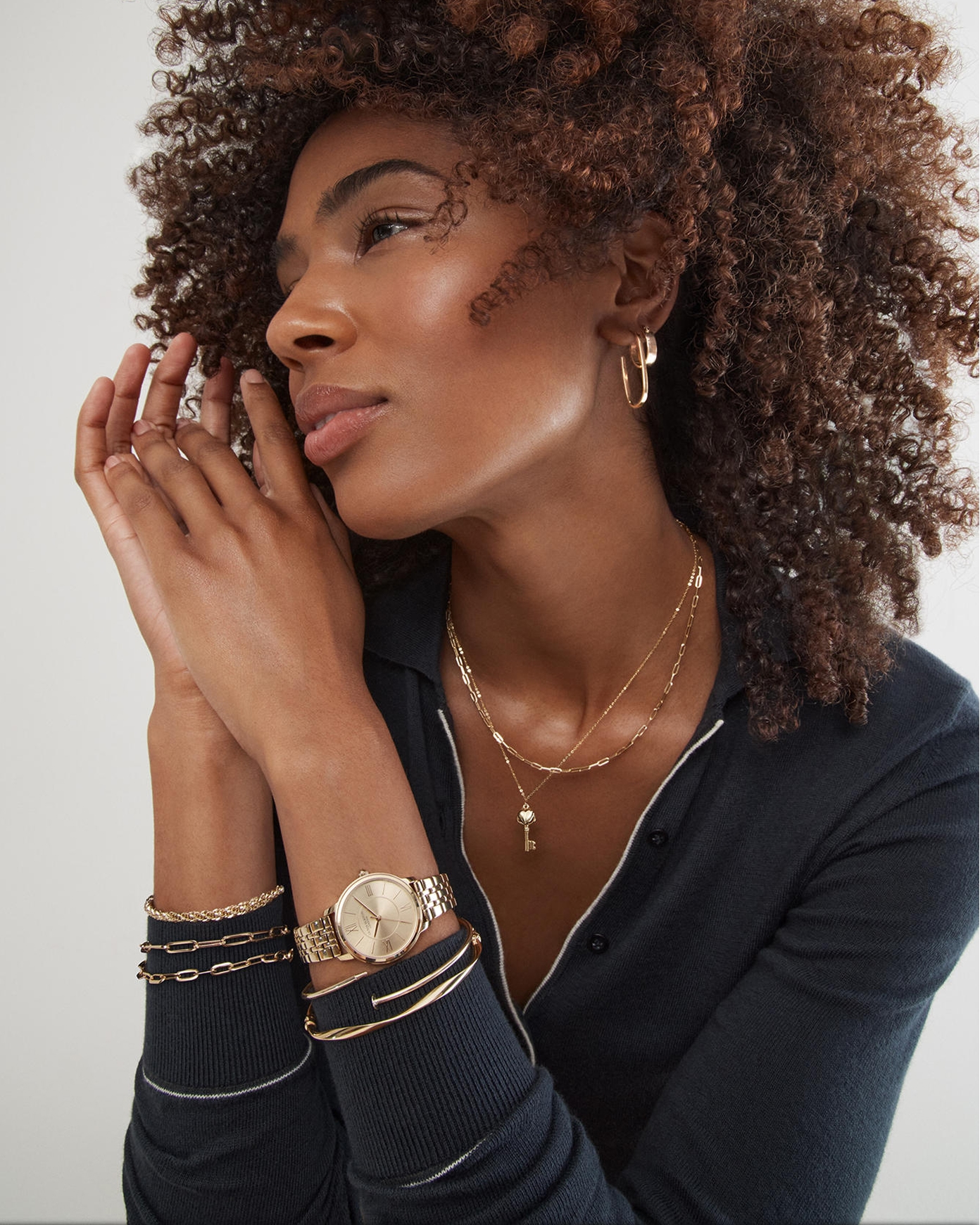 A woman wearing various gold jewelry pieces from KAY.