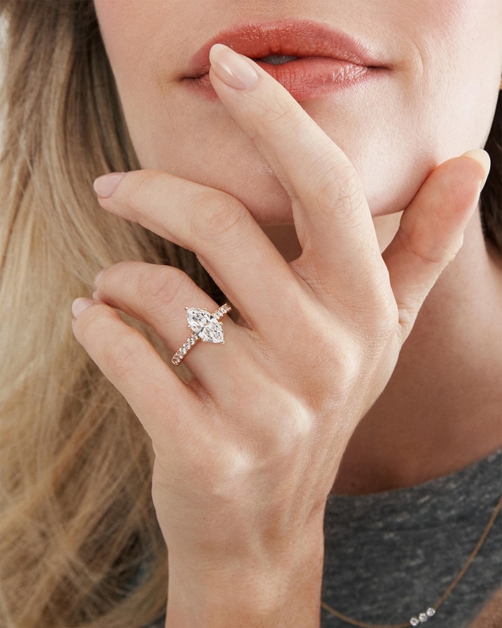 A woman with her hand on her face, showing off a marquise diamond engagement ring from KAY.