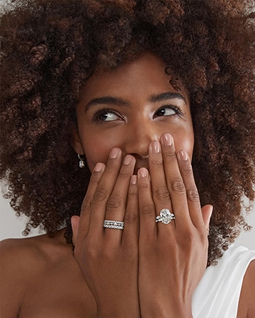 A women with her hands over her face showing off two diamond engagement rings from KAY.
