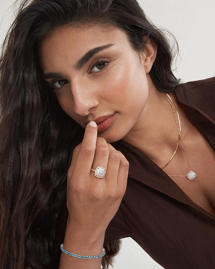 A model showing off he gemstone studded ring, tennis bracelet, and gold chain necklaces from KAY.