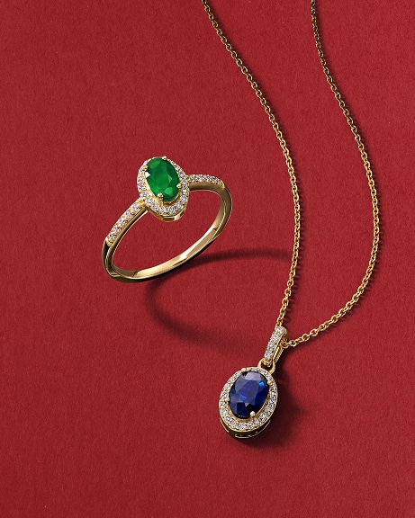 An emerald ring, and a sapphire pendant chain necklace, all in gold, from KAY.