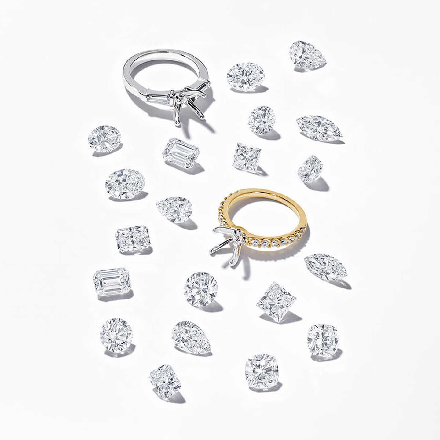 Two diamond engagement rings surrounded by a scattering of diamonds in different cuts.