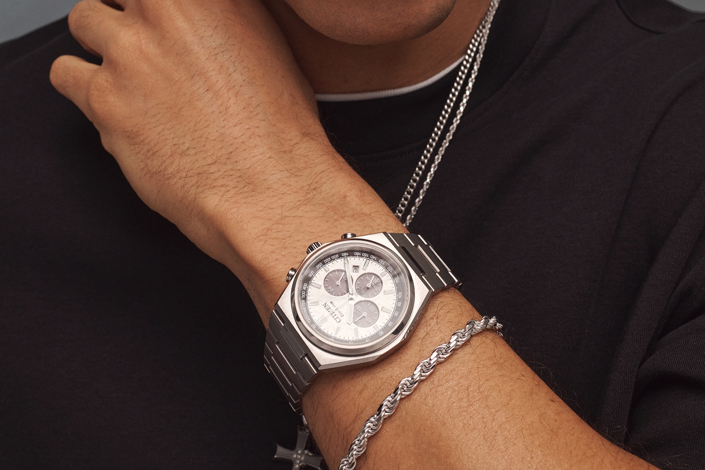 A man wearing two sterling silver chain necklaces and a stainless steel watch from KAY.