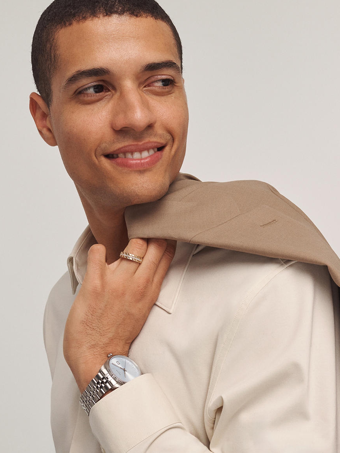 A man draping his coat over his should, wearing a diamond ring and stainless steel watch from KAY.