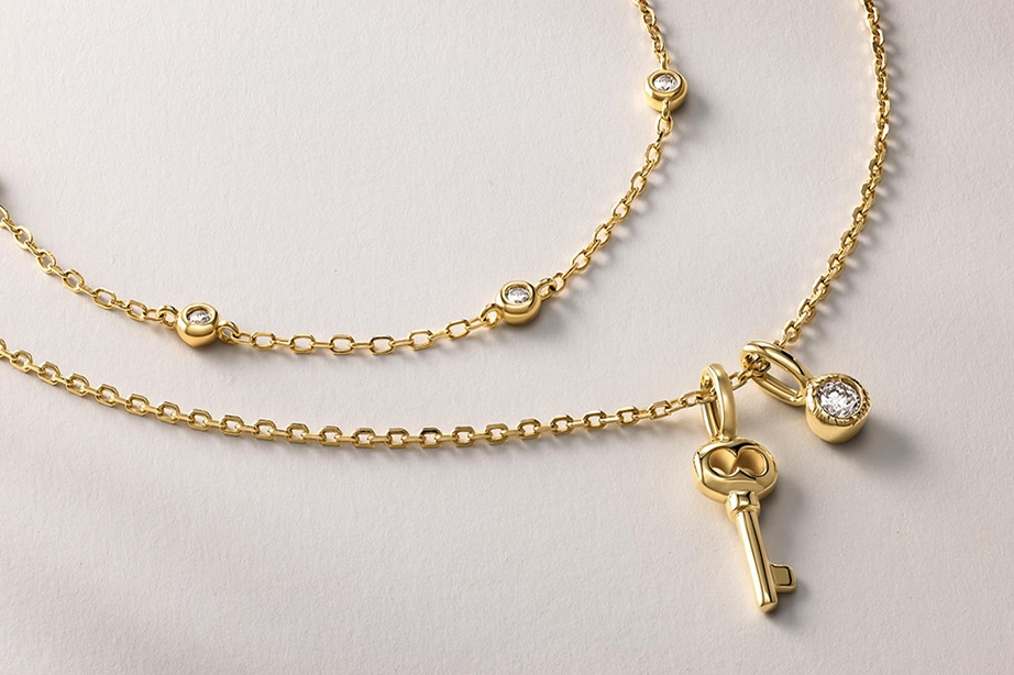 Two gold necklaces, one with a key pendant and a diamond pendant from KAY.