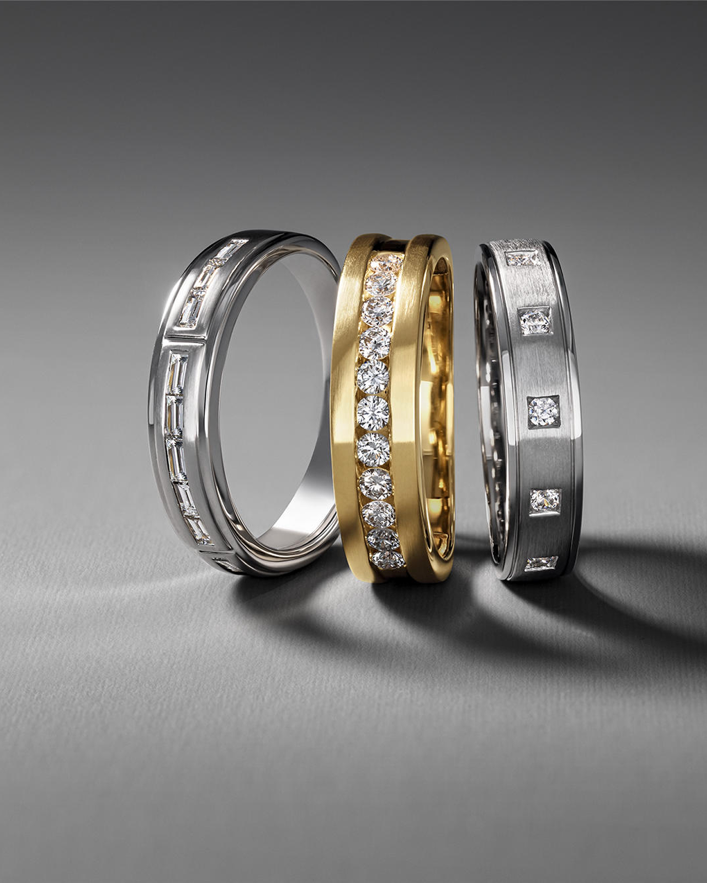 A custom gold wedding band surrounded by two custom silver engagement bands from KAY.