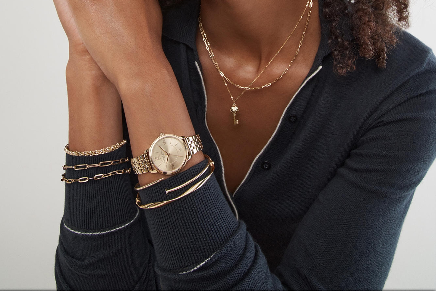 A woman sporting numerous pieces of gold jewelry from KAY.