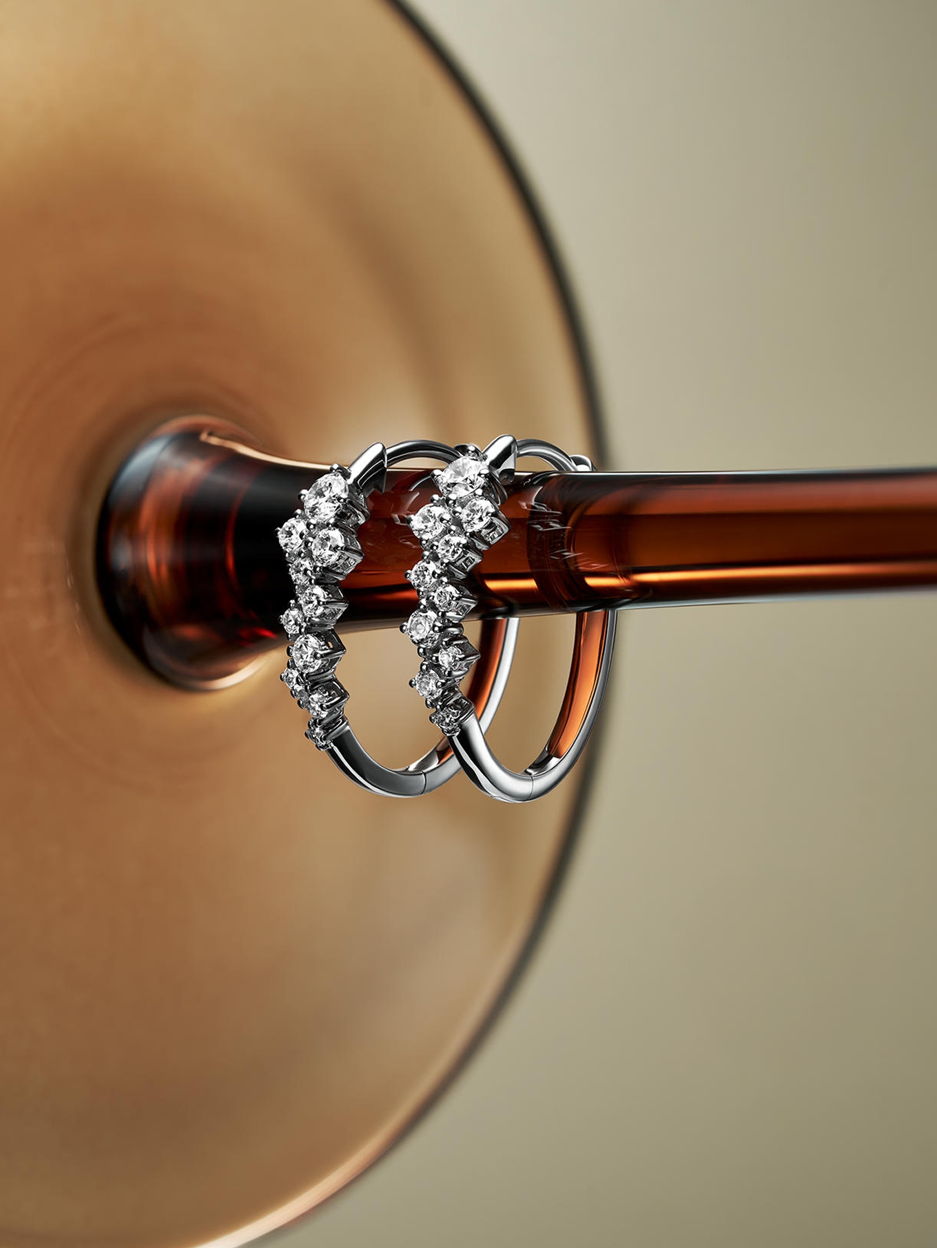 A pair of diamond earrings hanging from the stem of a wine glass, from KAY.