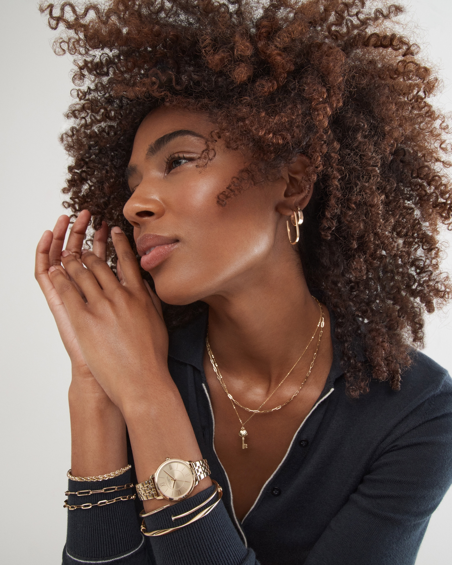 A woman showing off her gold and silver loop earrings from KAY.