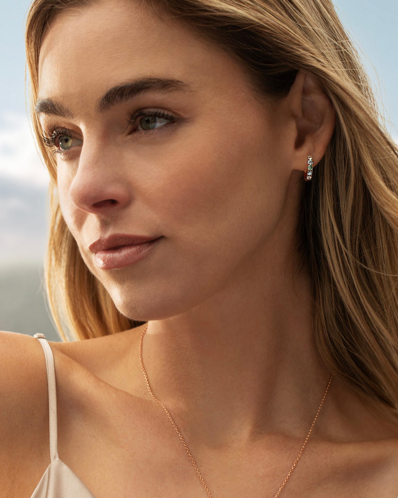 A woman wearing diamond earrings and a rose gold necklace by Le Vian, from KAY.