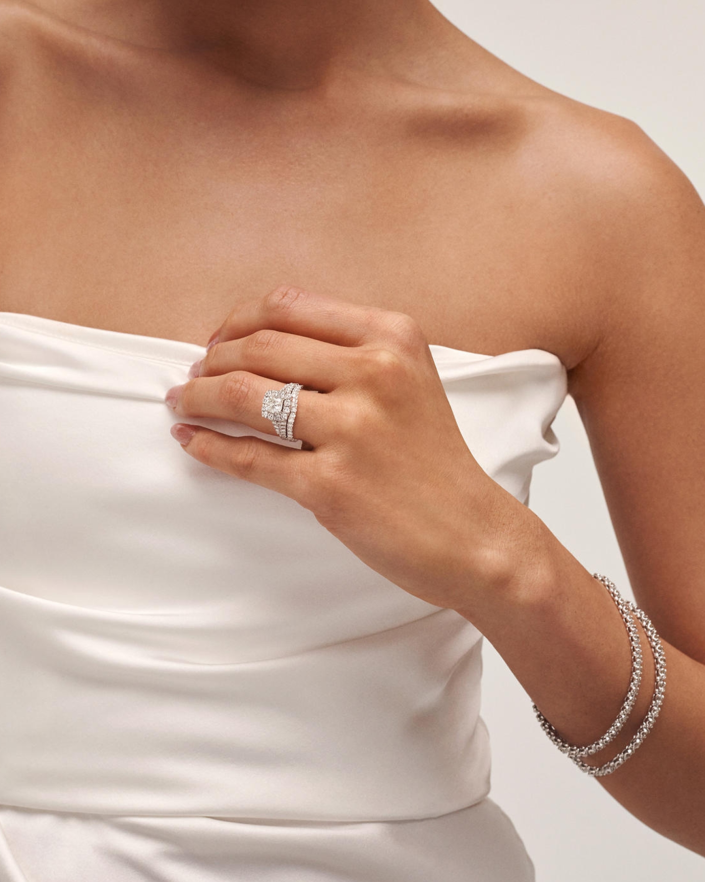 A woman showing off her natural, diamond, engagement ring and bracelets from KAY.