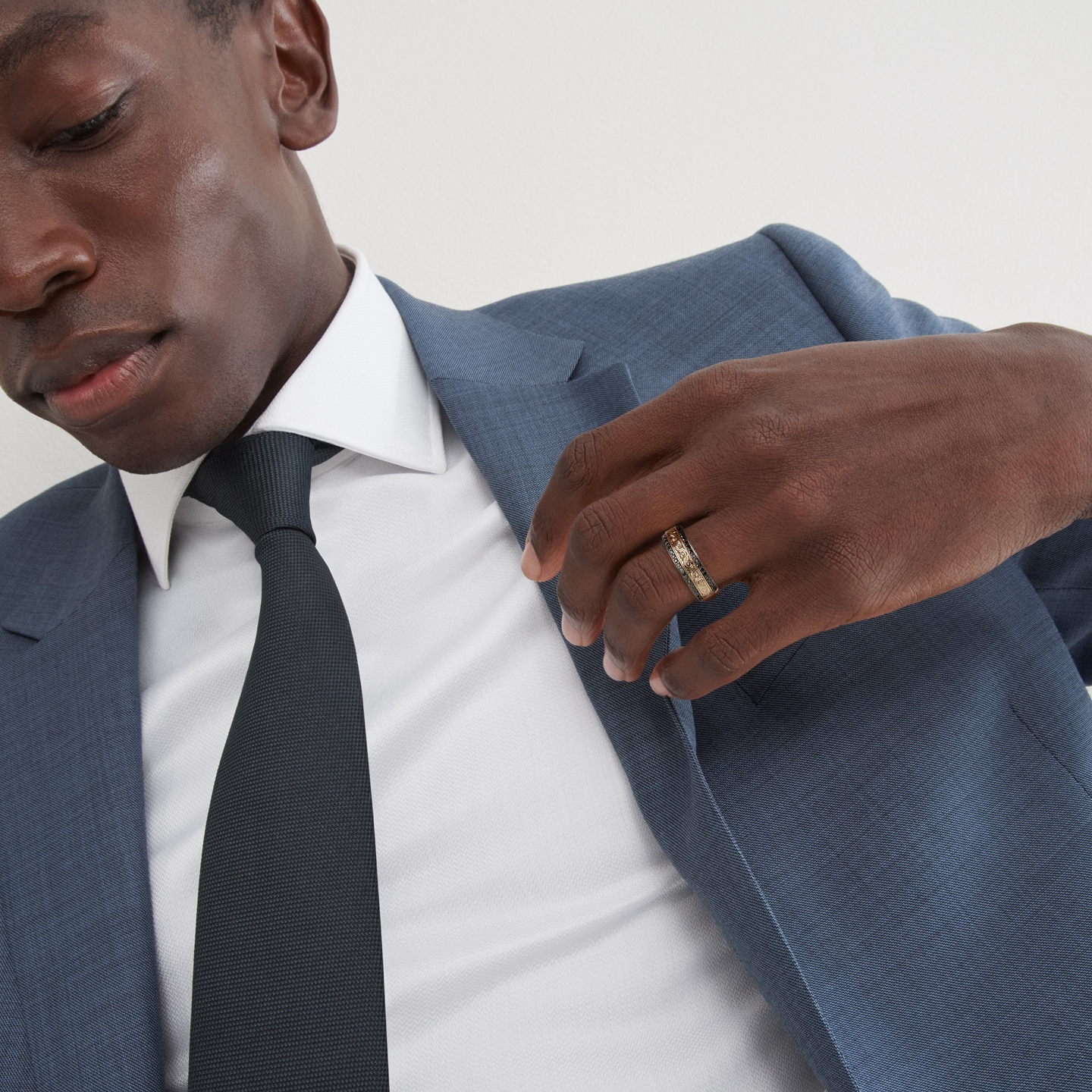 A man in a blue suit showing off his gold wedding ring from KAY.
