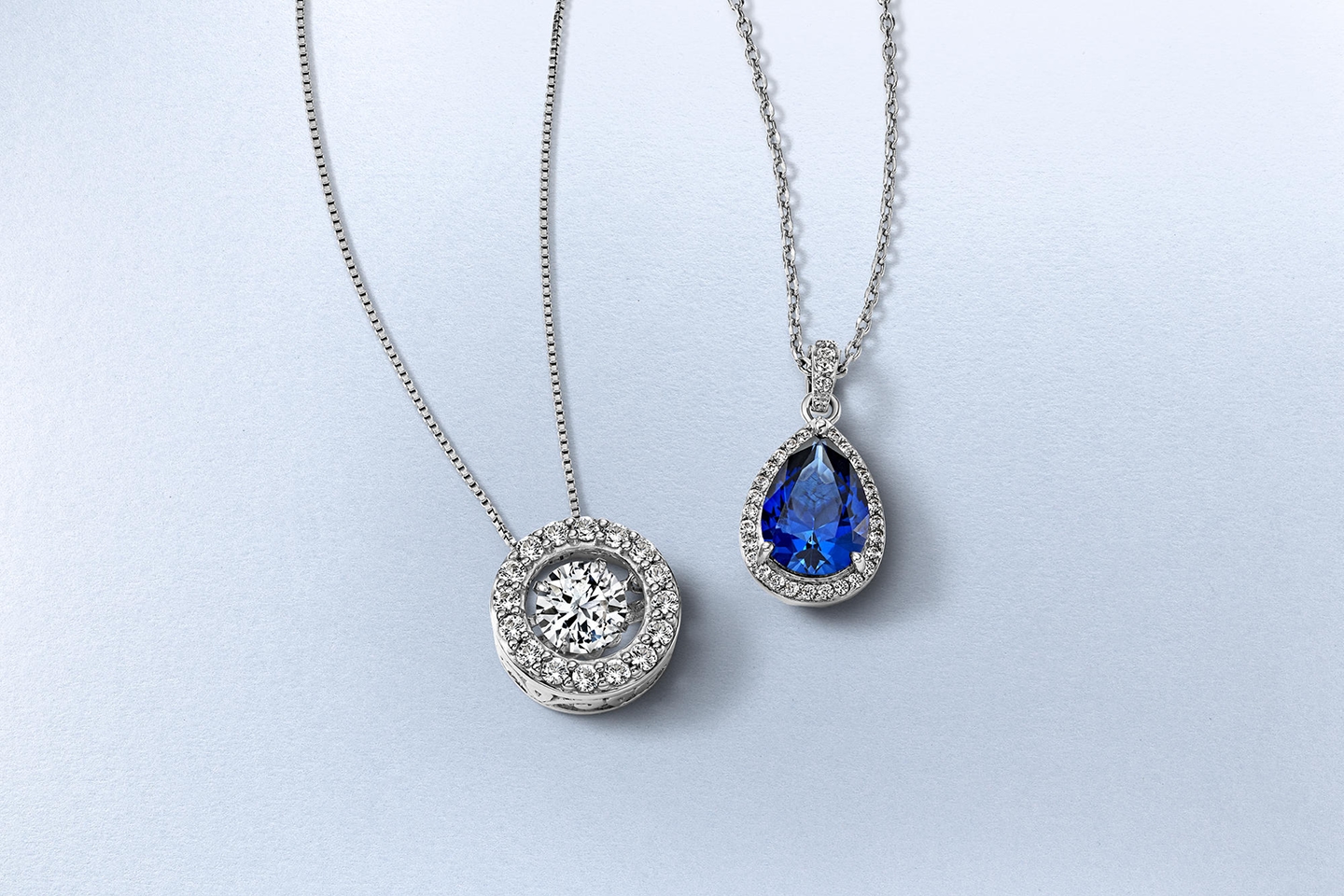Two silver necklaces from KAY. One with a diamond pendant, the other with a blue diamond pendant.