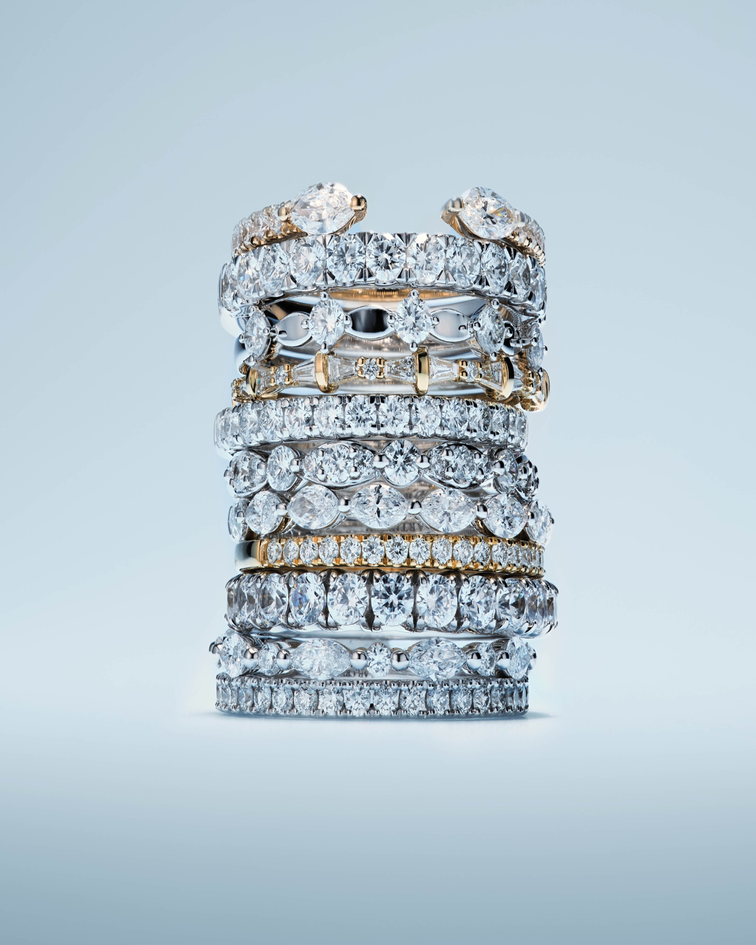 Eleven rings of varying metal color and stone type all stacked on one another from KAY.