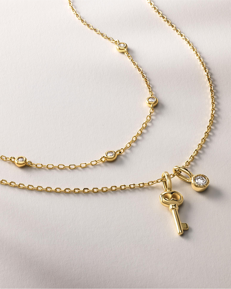 Two gold link necklaces, one with a golden key pendant from KAY.