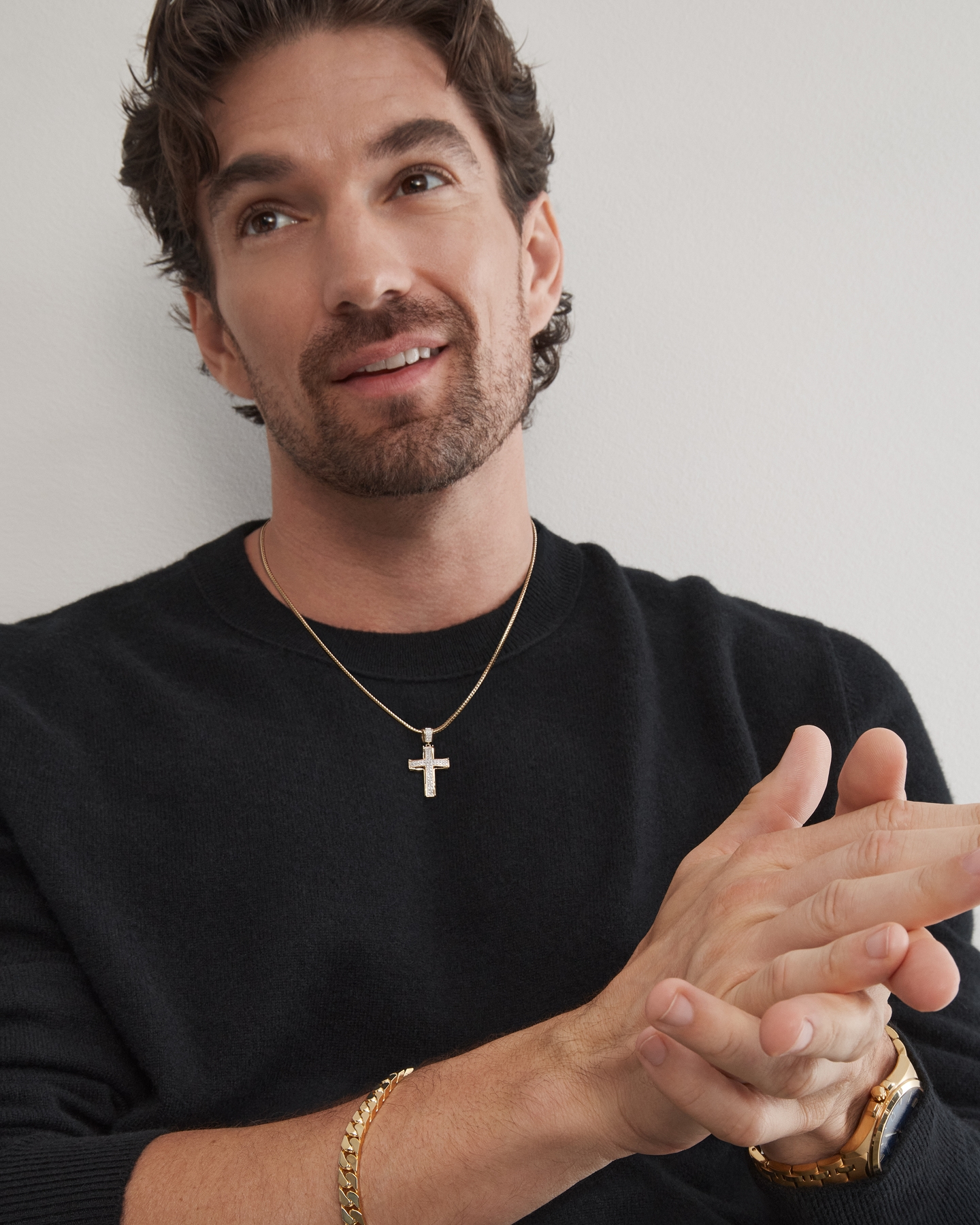 A man showing off his silver necklace with a cross pendant from KAY.