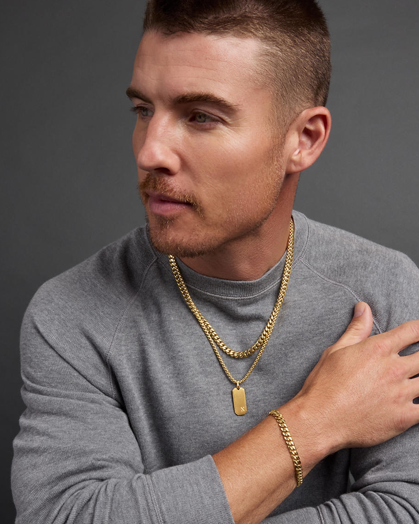 A man showing off his two gold chains and matching bracelet by Jaxxon, from KAY.