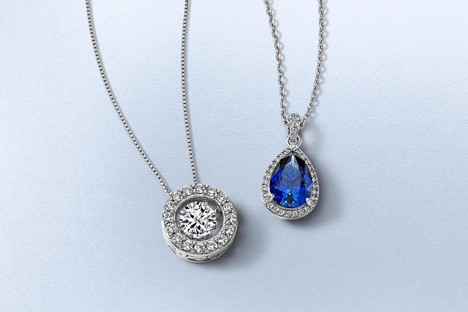Two necklaces from KAY. One with a diamond pendant attached to a silver chain. and the other a blue diamond attached to a silver chain.