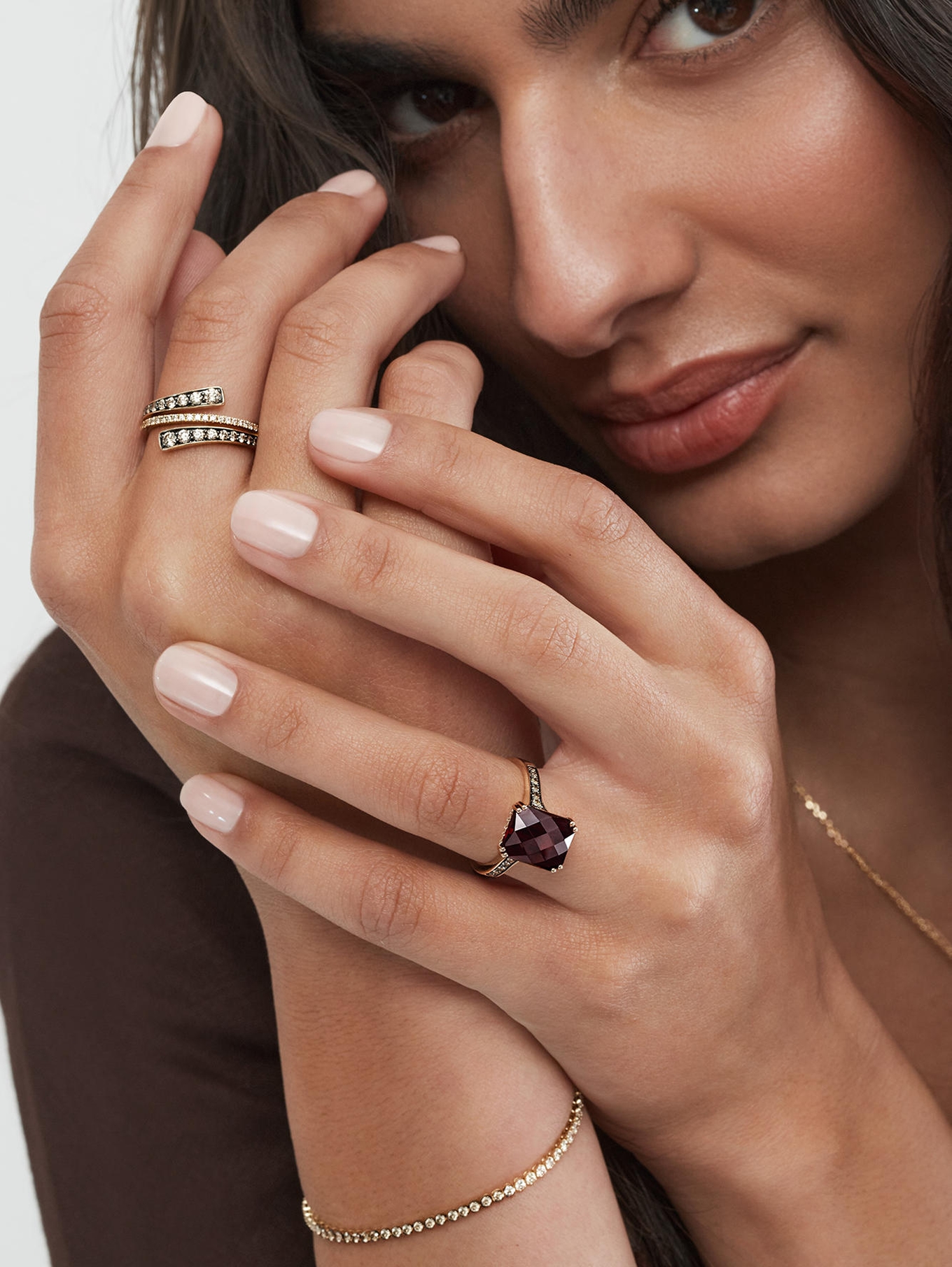 A woman with a spiraling, diamond ring and a deep, amethyst ring from KAY.