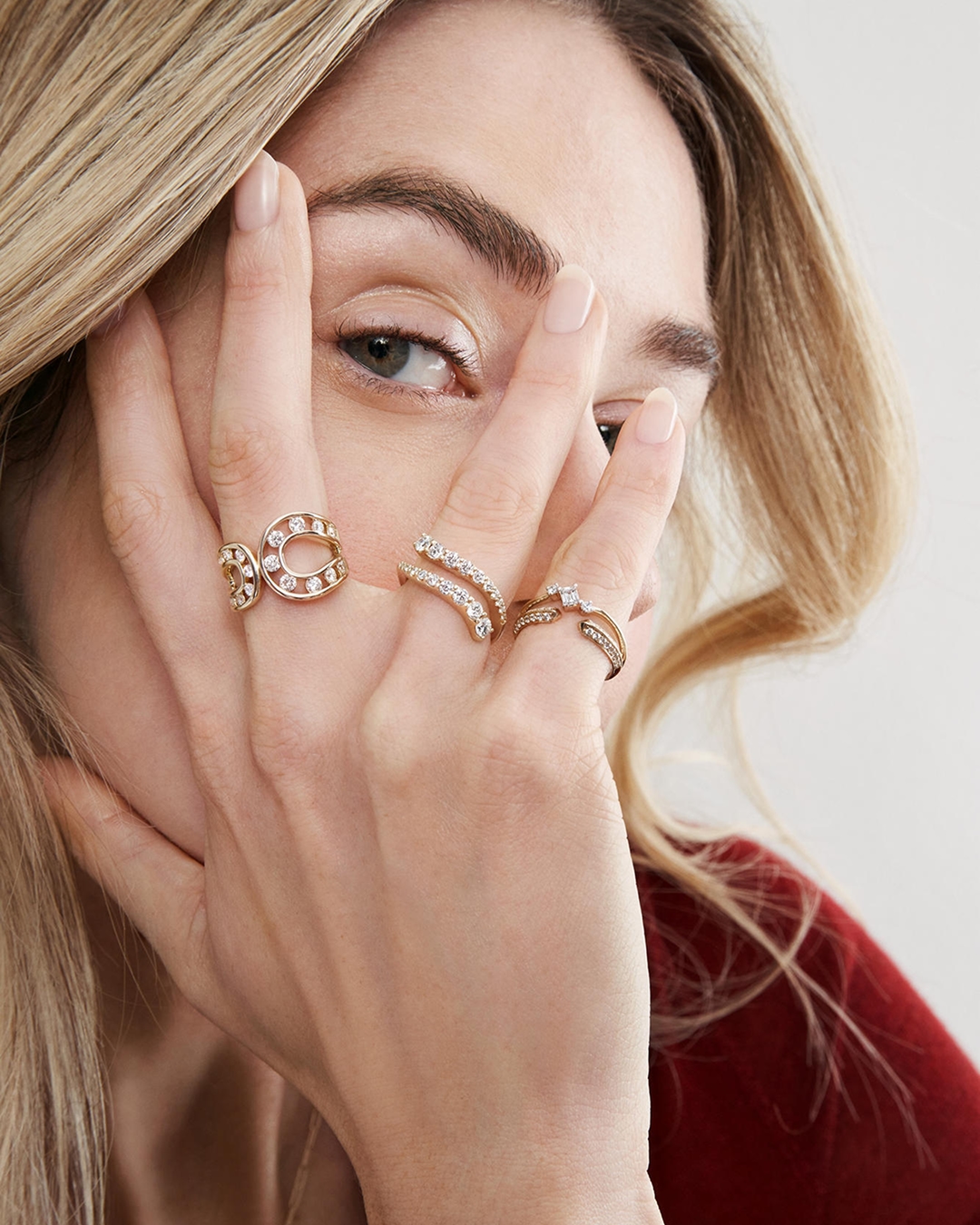 A woman showing off three differing styles of gold banded, diamond rings from KAY.