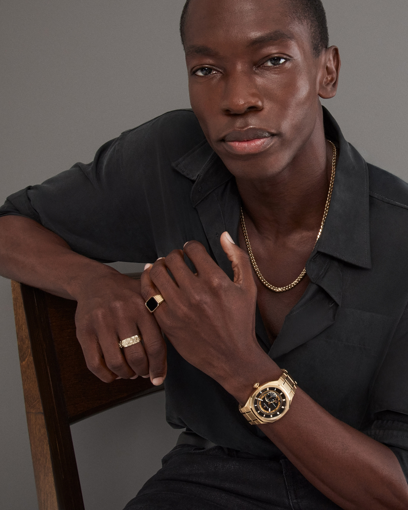 A man wearing various pieces of gold jewelry to match his gold, Bulova watch, from KAY.