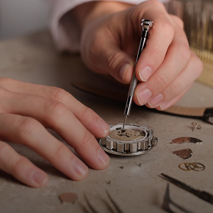 Close up of hands holding tool and repairing watch