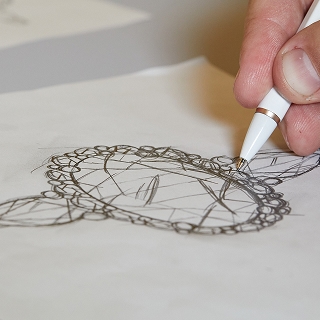Image of hand sketching engagement ring with a pen