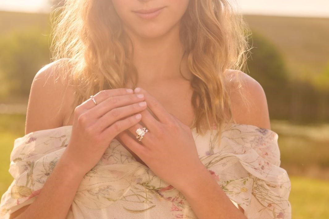 Image of woman in field wearing Monique Lhuillier Bliss engagement ring 